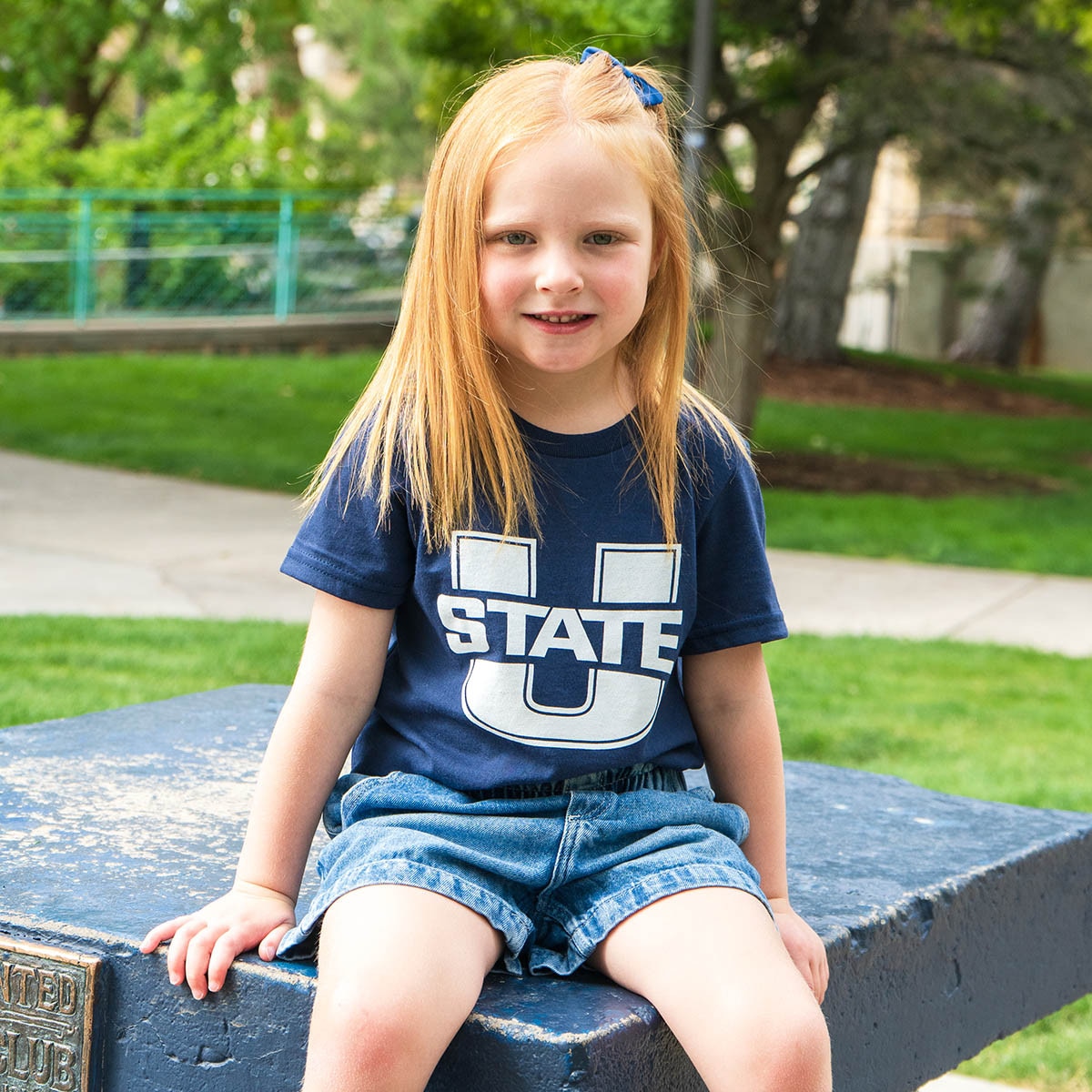 Young girl sitting on the block A wearing u-state navy t-shirt